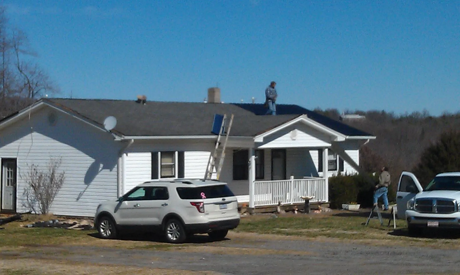 Roofers stripping shingles from a white ranch house roof in Rossville