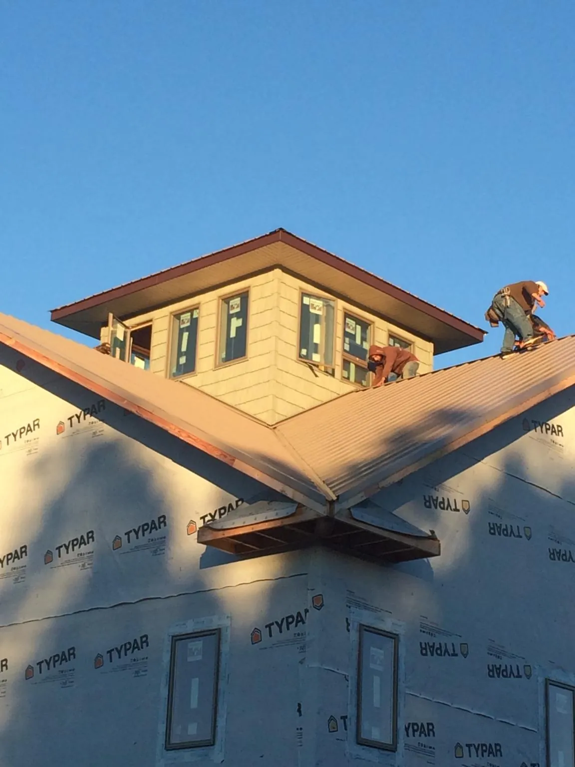 Roofers working around a rooftop cupola on a new metal roof at sunset — Roof Waterproofing in Rossville by Roofing Brothers